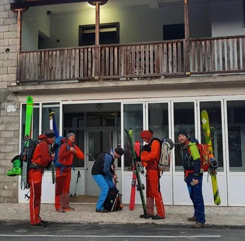 a group of men standing outside a building holding skis at Guest House Korabi in Ceren