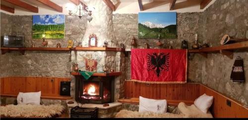 een woonkamer met een open haard en een rood gordijn bij Guest House Korabi in Ceren