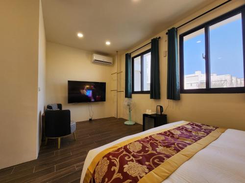 a bedroom with a bed and a flat screen tv at Penghu Dayou View B&B in Magong