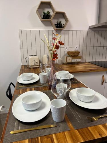 une table en bois avec des assiettes et des verres blancs dans l'établissement Bel T2 refait à neuf climatisé centre, à Brive-la-Gaillarde