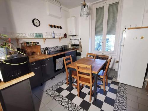 uma cozinha com uma mesa e cadeiras e um frigorífico em Charmant T2 avec jardin commun em Saint-Fons