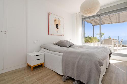 マルベーリャにあるTerrazas de Cabopinoの白いベッドルーム(ベッド1台、大きな窓付)