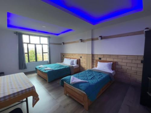 two beds in a room with a blue ceiling at JMS Resort in Cherrapunji