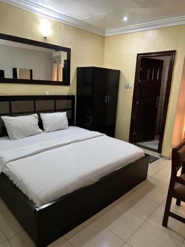 a bedroom with a large bed and a chair at Whitehouse Msquare Hotel in Ikeja