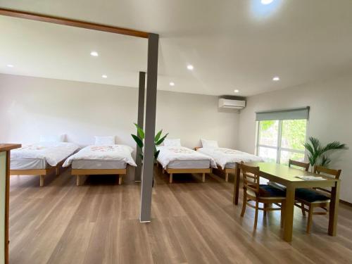 a room with four beds and a table and chairs at ゆふの音 in Yufuin