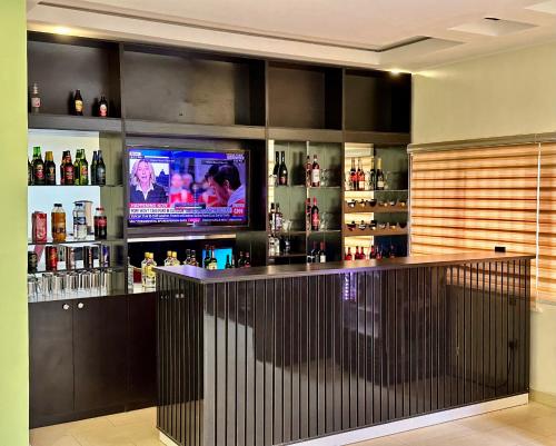 a bar with a television in a room at Whitehouse Msquare Hotel in Ikeja