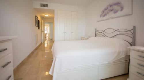 a white bedroom with a white bed and a hallway at Duquesa Village 7,19,12 in Manilva