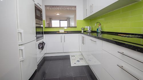 a kitchen with white cabinets and green walls at Duquesa Village 7,19,12 in Manilva