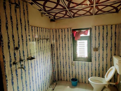 a bathroom with a toilet and a window at Tharu Lodge in Sauraha
