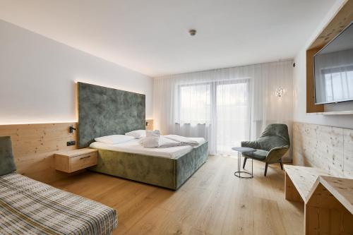 a bedroom with a bed and a chair in a room at Wellness-Sporthotel Ratschings in Racines