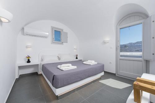 a white bedroom with a bed and a window at Golden View Suites in Vóthon