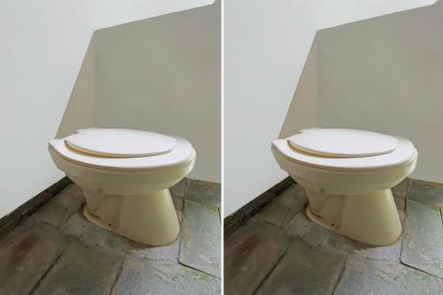 een wit toilet in een badkamer met een muur bij OYO 92419 Rejeng Homestay Near Kerta Gangga Waterfall in Luk