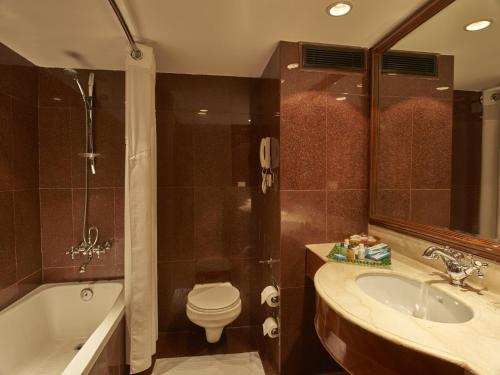 a bathroom with a sink and a toilet and a tub at Club Mahindra White Meadows Manali in Nagar