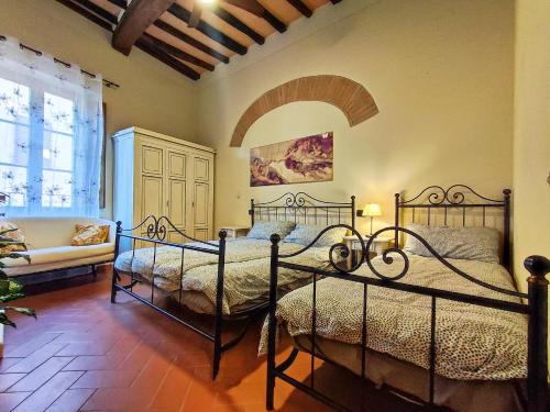 Casa Matteo San Gimignano Apartments في سان جيمنيانو: غرفة نوم بسريرين واريكة