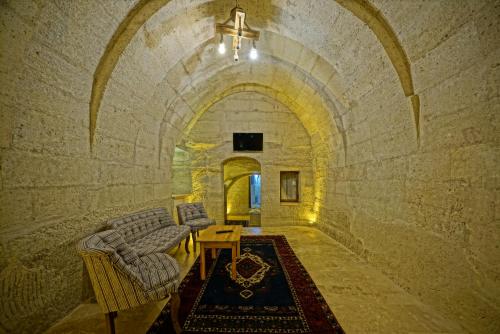 a stone tunnel with chairs and a table in a room at Cappa Cave Hotel in Goreme
