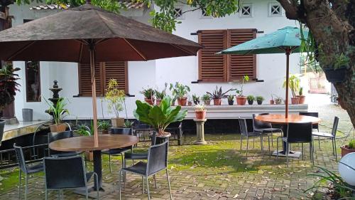 two tables and chairs with umbrellas in a courtyard at Valhalla Boutique Hotel in Salatiga