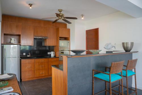 a kitchen with wooden cabinets and a ceiling fan at Villa Horizon by Dream Escapes, Beachfront Villa in Pointe aux Cannoniers