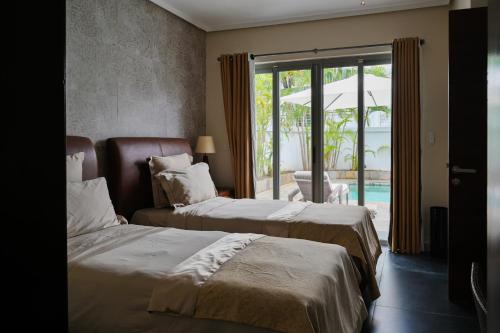 a hotel room with two beds and an umbrella at Villa Horizon by Dream Escapes, Beachfront Villa in Pointe aux Cannoniers