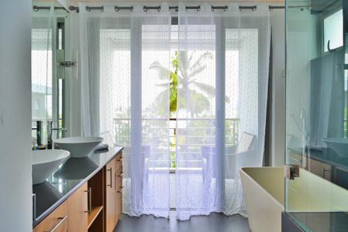 a bathroom with two sinks and a large window at Villa Horizon by Dream Escapes, Beachfront Villa in Pointe aux Cannoniers