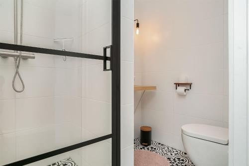 La salle de bains blanche est pourvue d'une douche et de toilettes. dans l'établissement B&B Unieck, à Koudum