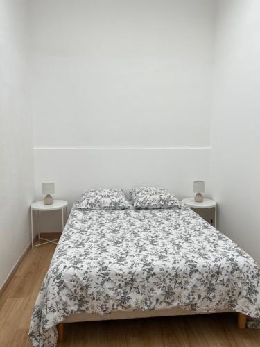 a white bedroom with a bed and two tables at Charmante maison au cœur du medoc in Cussac-Fort-Medoc