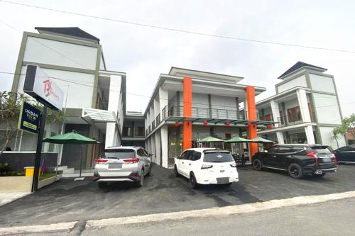 Urbanview Hotel Brodam's Pematang Siantar by RedDoorz في بيماتانغسياتار: سيارتين متوقفتين في موقف للسيارات امام مبنى