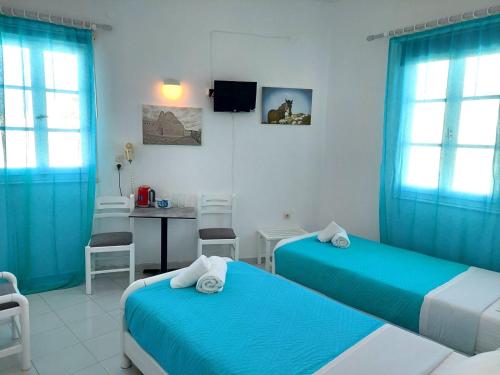una camera con due letti e un tavolo con sedie di Seatincenter Rooms a Mykonos Città