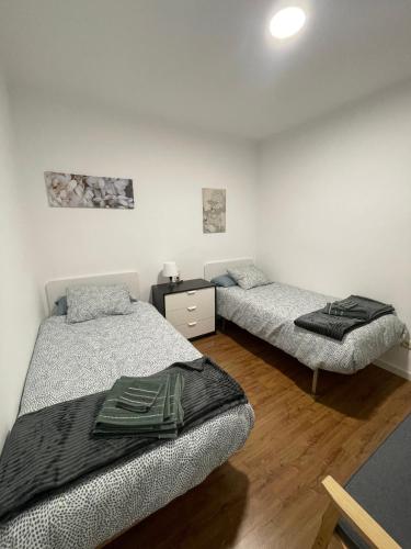 Duas camas num quarto com paredes brancas e pisos em madeira em Apartamento céntrico en Berga - ALBERGA em Berga