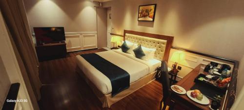 a hotel room with a bed and a television at Nambiar Club Bellezea in Bangalore