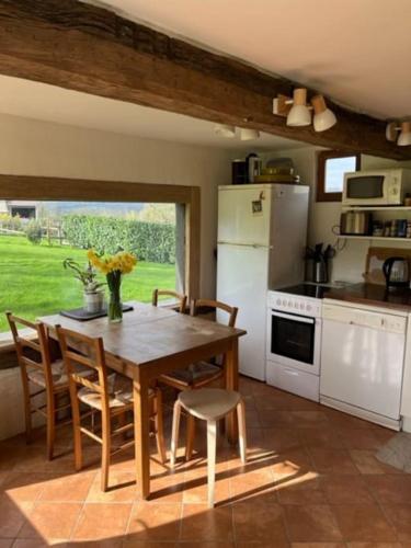 une cuisine avec une table et des chaises en bois et une cuisine avec des appareils blancs dans l'établissement Jolie longère normande pres d'Honfleur et de Deauville, à Les Authieux-sur-Calonne
