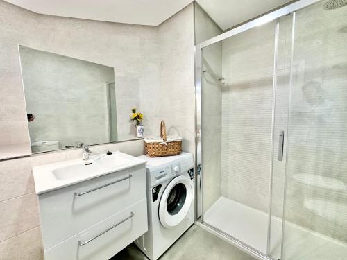 un bagno con lavatrice e lavandino di Cabopino Port - EaW Homes a Marbella
