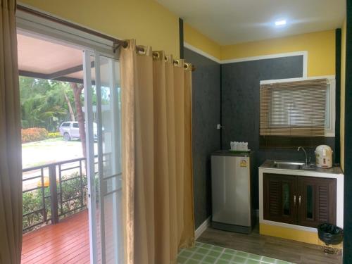 a kitchen with a refrigerator and a door to a balcony at Rayonghouse Resort in Rayong