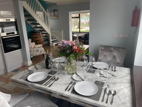 a table with plates and glasses and a vase of flowers at Mourne View in Killough