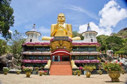 budynek z dużym złotym posągiem przed nim w obiekcie Chandi Relax Hostel w mieście Sigirija