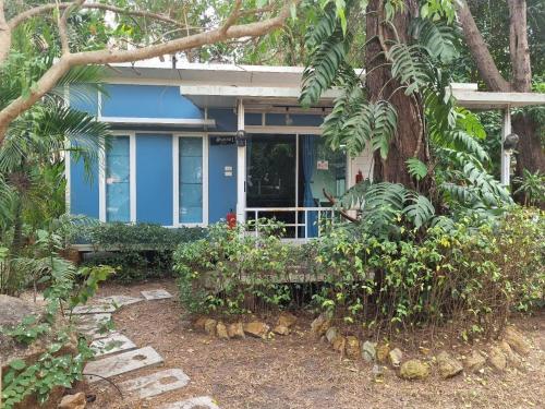 a blue house with a bench in front of a tree at Rayonghouse Resort in Rayong