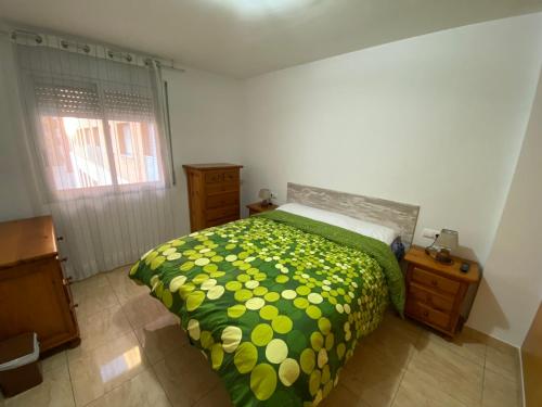 ein Schlafzimmer mit einem Bett mit einer grünen und gelben Tagesdecke in der Unterkunft Joan XXIII Apartment in Tarragona