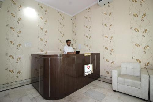 a man standing at a reception desk in a room at Super Capital O Hotel Paradise Residency in Rāmnagar