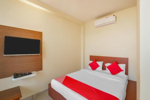 a bedroom with a bed with red pillows and a tv at OYO Jk Inn in Narasimharaja Puram