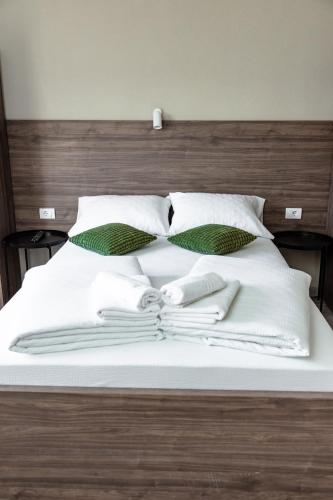 a bed with white blankets and pillows on it at Đerdan Garden apartments in Kraljevo