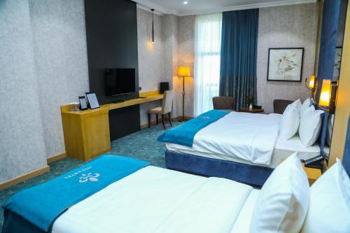 a hotel room with two beds and a television at Iris Hotel Baku in Baku