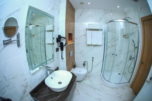 a bathroom with a sink and a shower and a toilet at Iris Hotel Baku in Baku