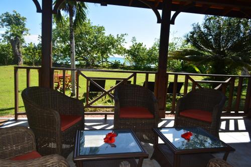 a porch with chairs and tables with roses on them at Heliconia Grove in Baie Sainte Anne