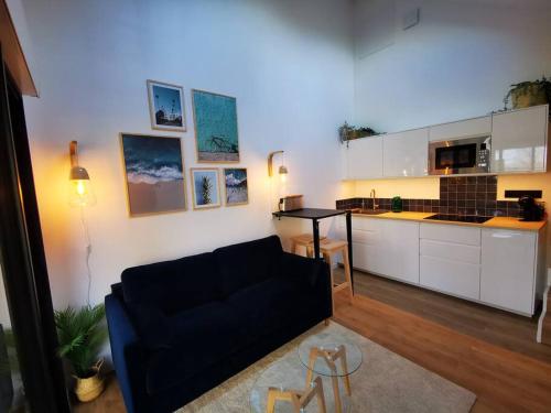 un salon avec un canapé noir et une cuisine dans l'établissement Gîte avec Spa, à Saint-Marcan