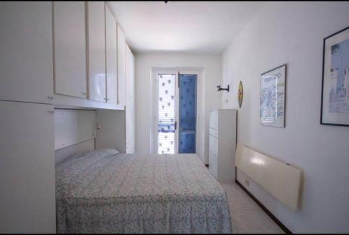 Habitación blanca con cama y nevera. en Bilocale con ampio terrazzo, en Marciana Marina