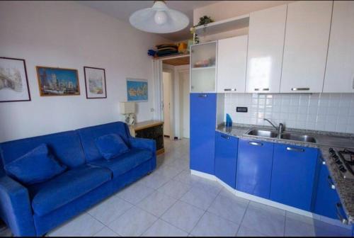 Una sala de estar con un sofá azul y una cocina. en Bilocale con ampio terrazzo, en Marciana Marina