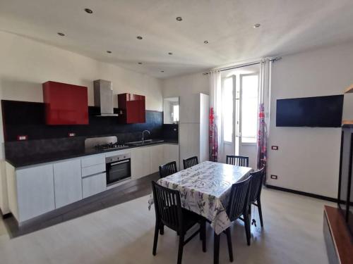 une cuisine avec une table, des chaises et des armoires rouges dans l'établissement La casa del Lubra, à Piombino