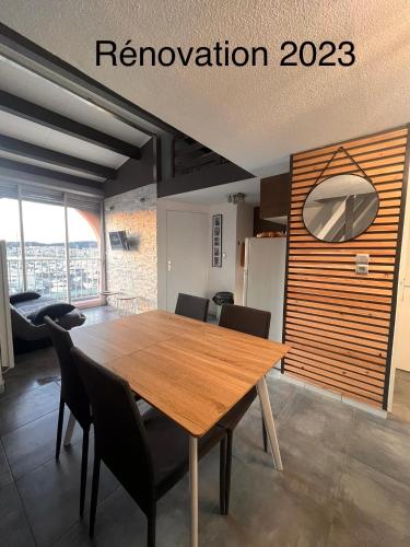 une salle à manger avec une table et des chaises en bois dans l'établissement Belle vue, T2 Mezzanine vue port, 50 m de la plage de la conque, au Cap d'Agde