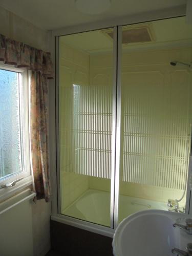 a bathroom with a glass shower and a sink at 10 Berth on Coastfields with free WiFi Status in Ingoldmells