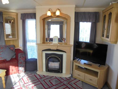 a living room with a fireplace and a tv at 10 Berth on Coastfields with free WiFi Status in Ingoldmells