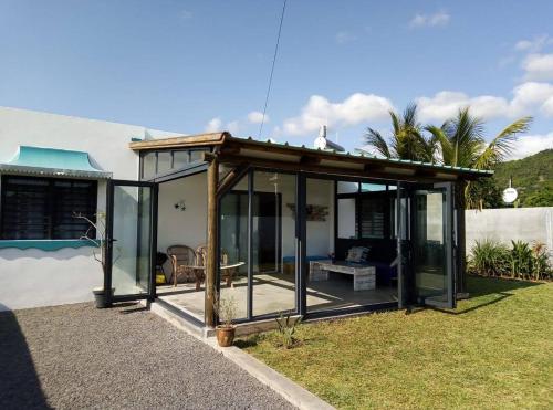 a conservatory with glass doors in a yard at Cozy house for Kite & windsurfers (Le Morne) in Le Morne